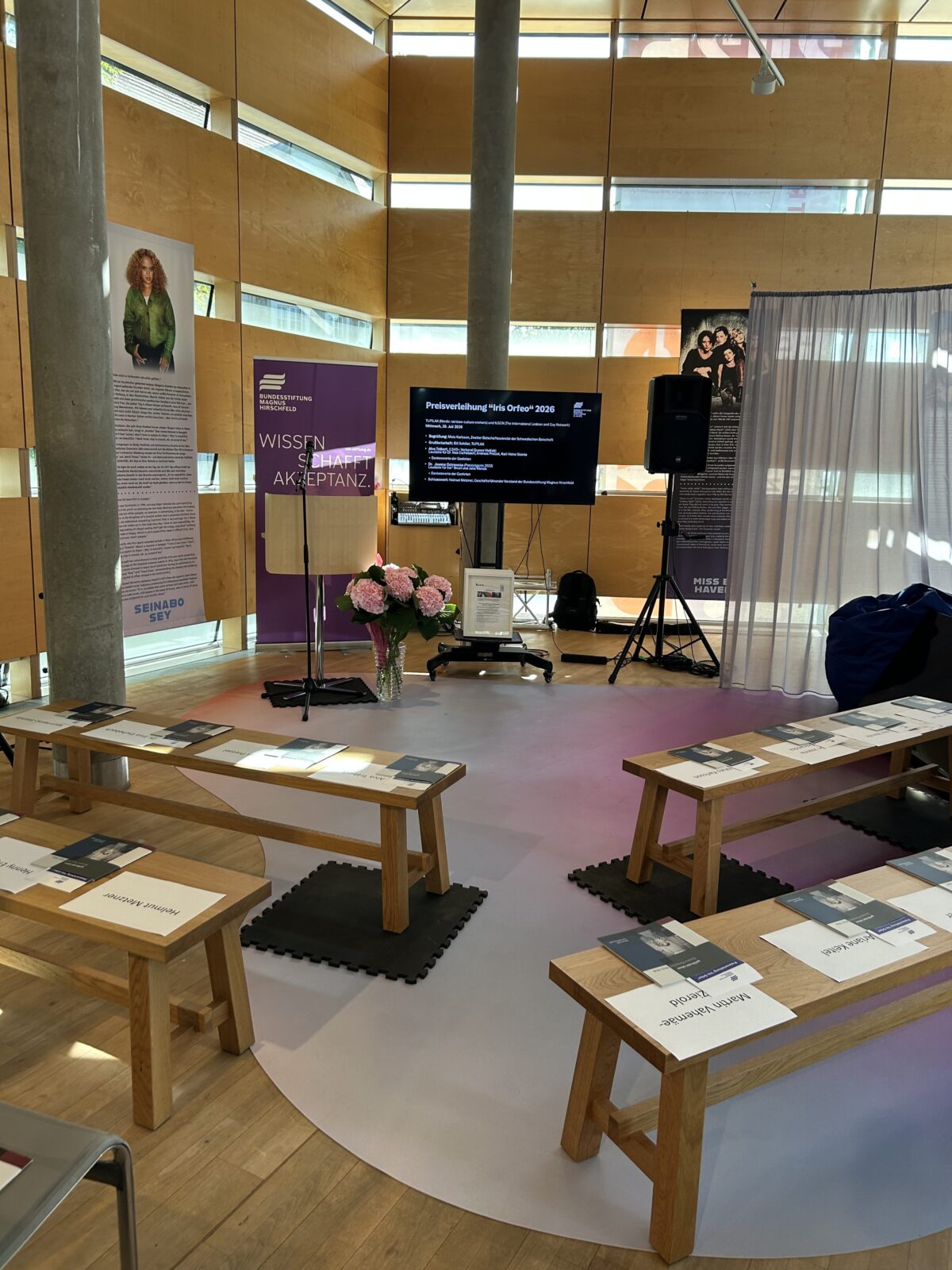 Foto. Zu sehen ist die feierliche Zeremonie anlässlich der Verleihung des Iris-Orfeo-Award in der Schwedischen Botschaft Berlin. Im Vordergrund: Bänke, auf denen das Begleitheft der BMH-Auststellung 