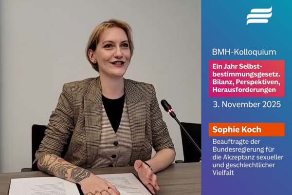 Screenshot des Videos “Grußwort im Rahmen des BMH-Kolloquiums zu 1 Jahr Selbst­bestimmungs­gesetz”. Zu sehen ist Sophie Koch neben einem Mikrofon.