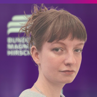 Portraitfoto Klara Heichen Im Hintergrund ist verschwommen das Logo der Bundesstiftung Magnus Hirschfeld in weiß vor lila Hintergrund zu erkennen.